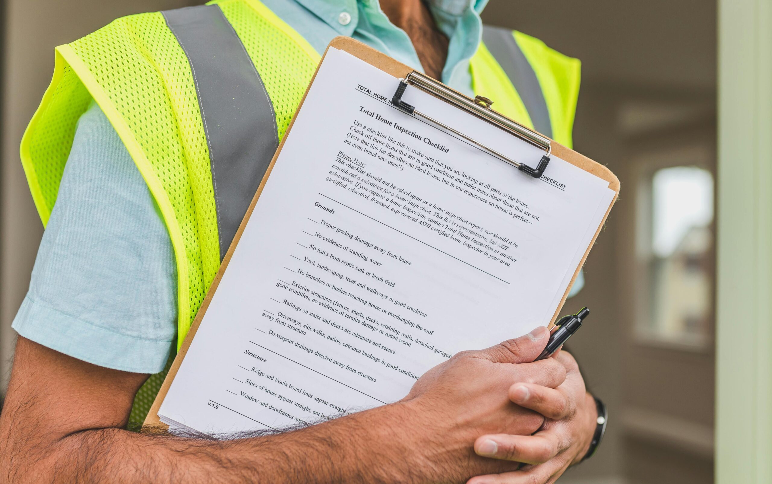 Close-up of home inspector holding a checklist on a clipboard with a pen.